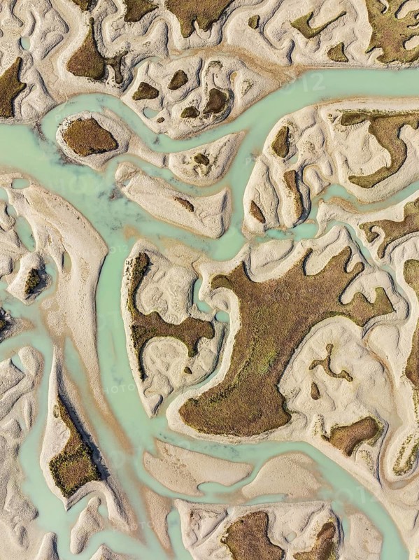 Network of channels and streams at low tide. In the marshland of the Bahía de Cádiz Nature Reserve. Aerial view. Drone shot. Cádiz province, Andalusia, Spain