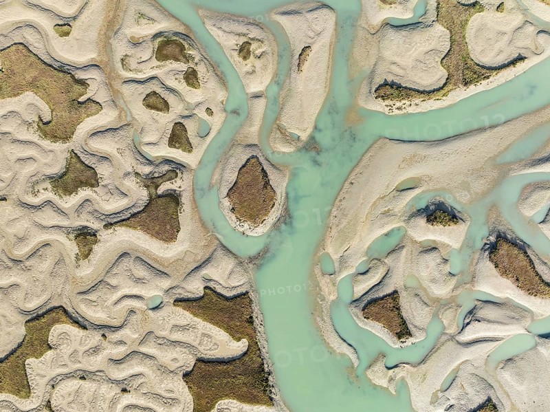 Network of channels and streams at low tide. In the marshland of the Bahía de Cádiz Nature Reserve. Aerial view. Drone shot. Cádiz province, Andalusia, Spain