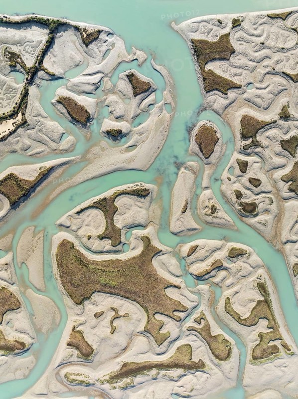 Network of channels and streams at low tide. In the marshland of the Bahía de Cádiz Nature Reserve. Aerial view. Drone shot. Cádiz province, Andalusia, Spain