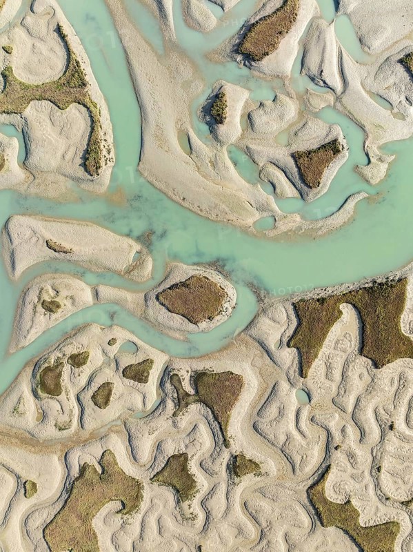 Network of channels and streams at low tide. In the marshland of the Bahía de Cádiz Nature Reserve. Aerial view. Drone shot. Cádiz province, Andalusia, Spain
