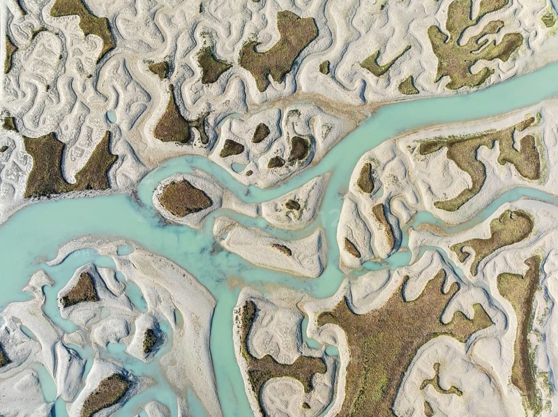 Network of channels and streams at low tide. In the marshland of the Bahía de Cádiz Nature Reserve. Aerial view. Drone shot. Cádiz province, Andalusia, Spain