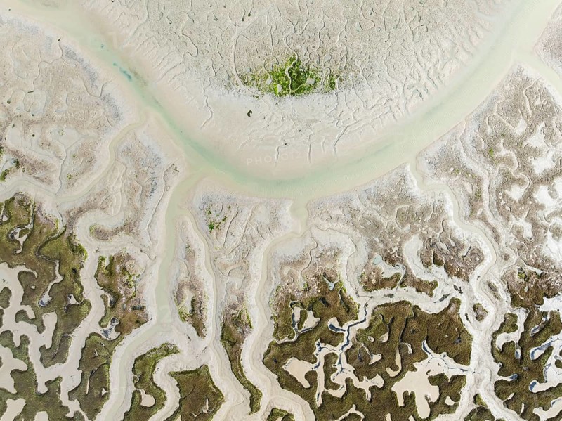 Network of dry channels and streams at low tide. In the marshland of the Bahía de Cádiz Nature Reserve. Aerial view. Drone shot. Cádiz province, Andalusia, Spain