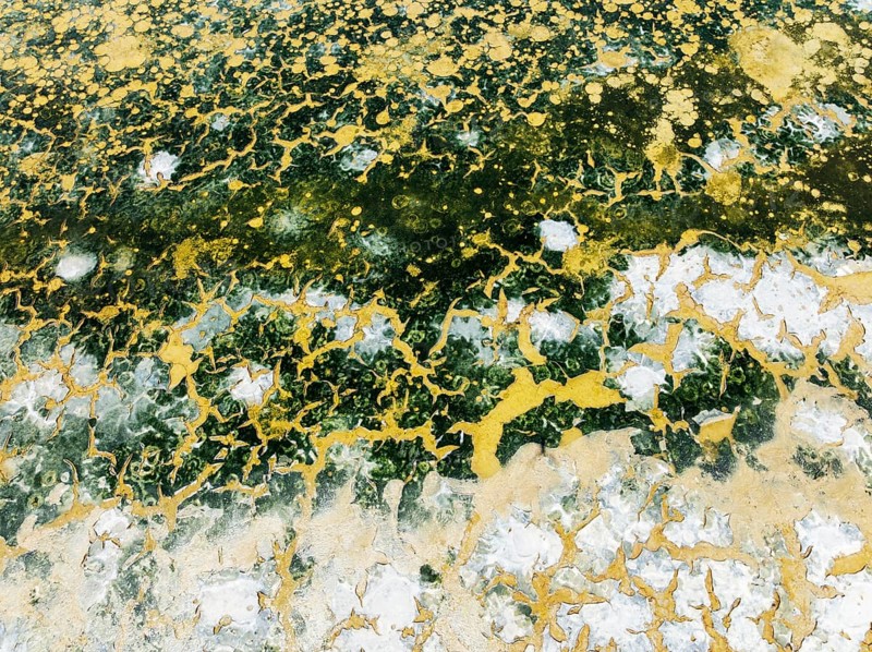 Abstract patterns in the shallow water of a saline pond in the marshland of the Bahía de Cádiz Nature Reserve. Aerial view. Drone shot. Cádiz province, Andalusia, Spain