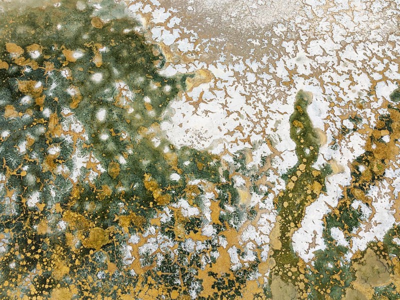 Abstract patterns in the shallow water of a saline pond in the marshland of the Bahía de Cádiz Nature Reserve. Aerial view. Drone shot. Cádiz province, Andalusia, Spain