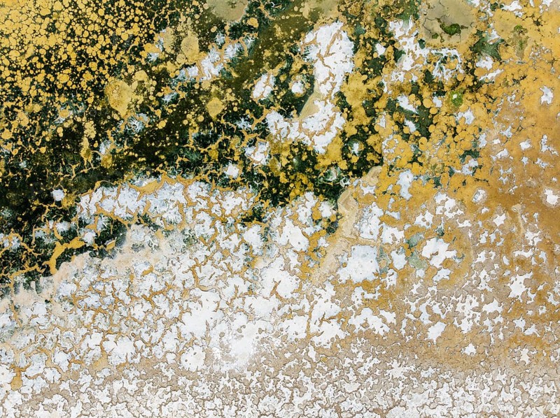 Abstract patterns in the shallow water of a saline pond in the marshland of the Bahía de Cádiz Nature Reserve. Aerial view. Drone shot. Cádiz province, Andalusia, Spain