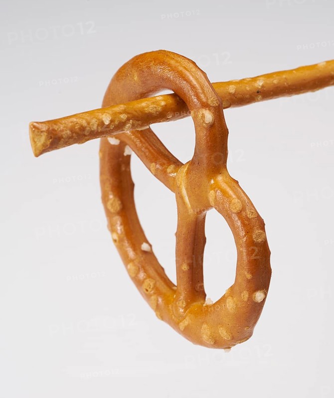 Small lye pretzel hanging on a salt stick in light back