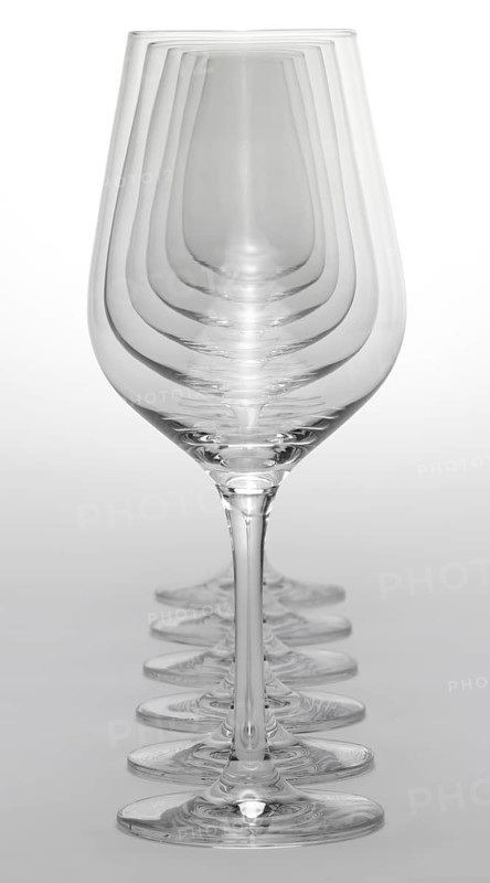 Some clean and empty wine glasses standing in a row in light grey back