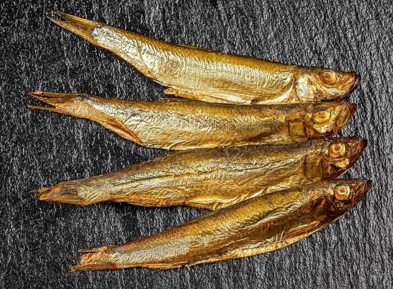 Arrangement with fresh smoked sprats on dark stone slab