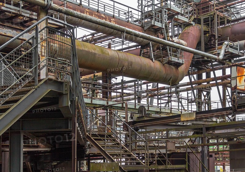 Weathered rundown industrial scenery with old corroded steel girders, stairs and metal tubes