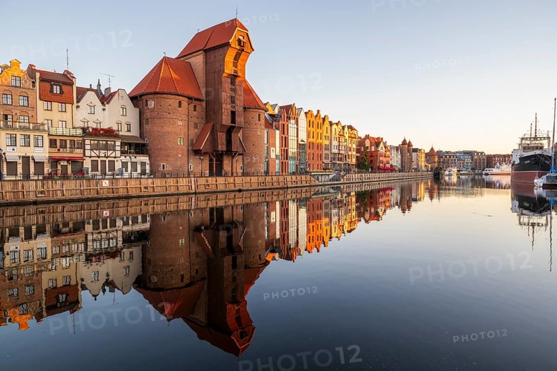 Waterfront promenade with reflection at sunrise in the Old Town, Brama Zuraw crane gate, Motlawa River, Gdansk, Gdansk, Poland