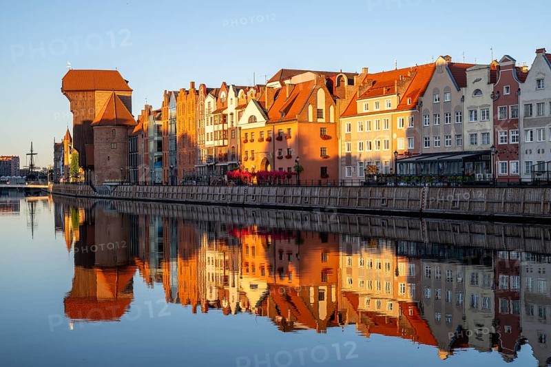 Waterfront promenade with reflection at sunrise in the Old Town, Brama Zuraw crane gate, Motlawa River, Gdansk, Gdansk, Poland
