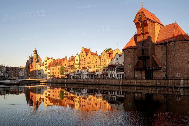 Waterfront promenade with reflection at sunrise in the Old Town, Brama Zuraw crane gate, Motlawa River, Gdansk, Gdansk, Poland