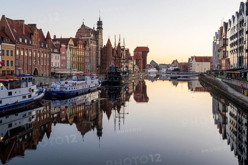 Waterfront promenade with reflection at sunrise in the Old Town, Brama Zuraw crane gate, Motlawa River, Gdansk, Gdansk, Poland