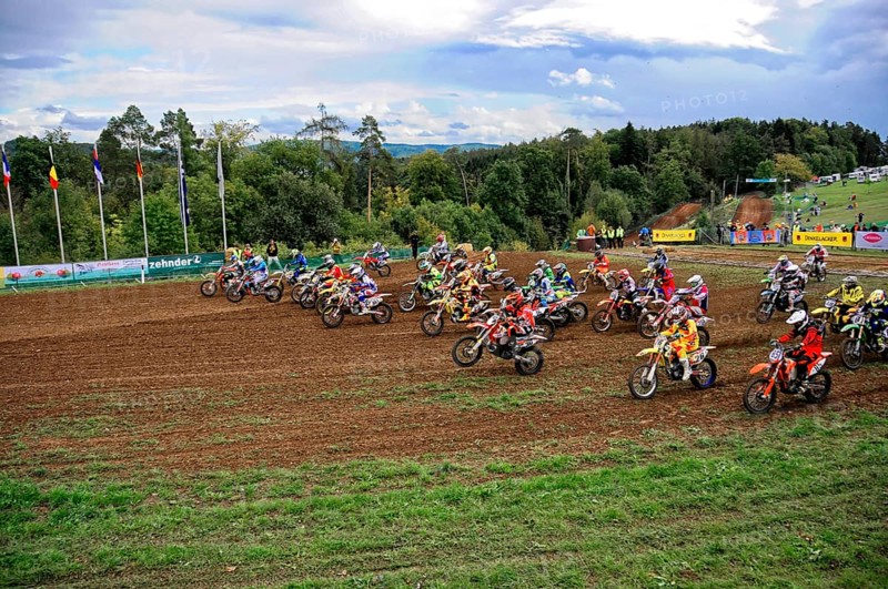 Motocross, Rudersberg, Baden-Württemberg, Germany, Europe, Motocross riders accelerate after the start of a race, surrounded by green landscape and flags, Rudersberg motocross