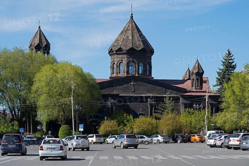 A black church with old architecture and parked cars in a green setting, Cathedral of the Holy Mother of God, Our Lady of the Seven Wounds, Gyumri, Gyumri, Shirak Province, Armenia