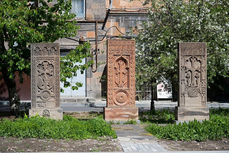 Three artistically engraved khachkars stand in a green setting, cross stones, khachkars, Gyumri, Gyumri, Shirak Province, Armenia
