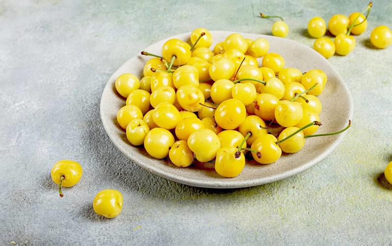 Yellow cherry, cherry berry, scattered on a plate, top view, no people