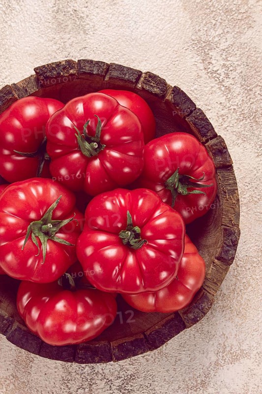 Pink tomatoes, in a rustic wooden bowl, close-up, no people
