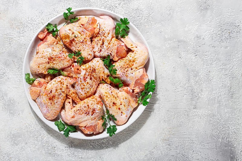 Marinated chicken wings prepared for grilling with spices and fresh herbs ready for cooking