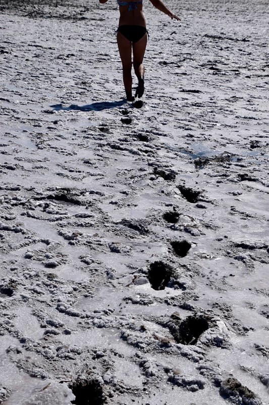 Woman walking along the dry bottom of a salt lake, rear view. Taman, Krasnodar Krai, Russia