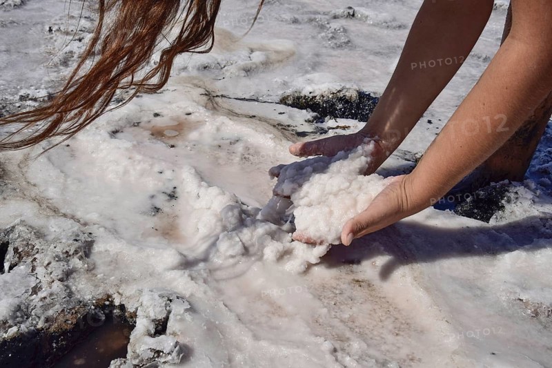 Hands girls taking on the wet salt from the puddles. Taman, Krasnodar Krai, Russia