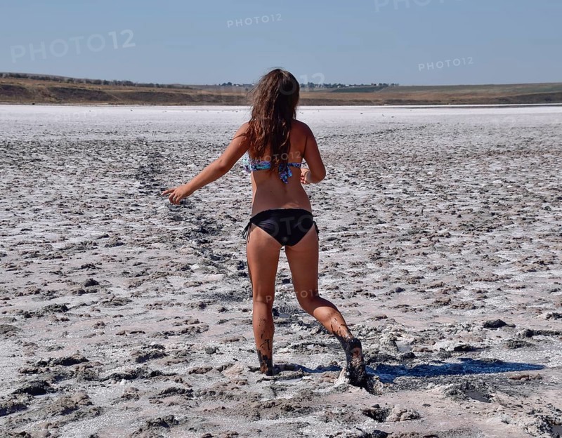 Woman walking along the dry bottom of a salt lake, rear view. Taman, Krasnodar Krai, Russia