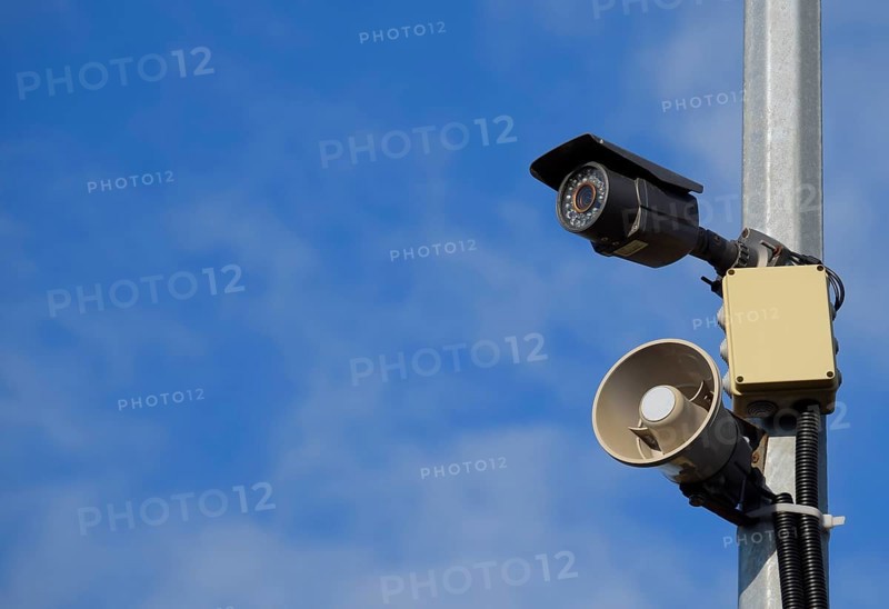CCTV camera and loudspeaker alarm on a pole against a blue sky. Taman, Krasnodar Krai, Russia