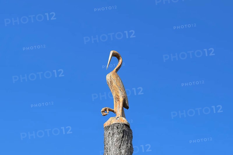 Figure of crane on the stump of a tree against the blue sky. Taman, Krasnodar Krai, Russia