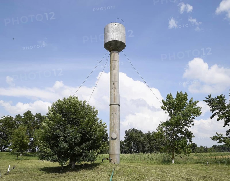 Silver Water Tower among green grass and trees. Atyrau, Kazakhstan