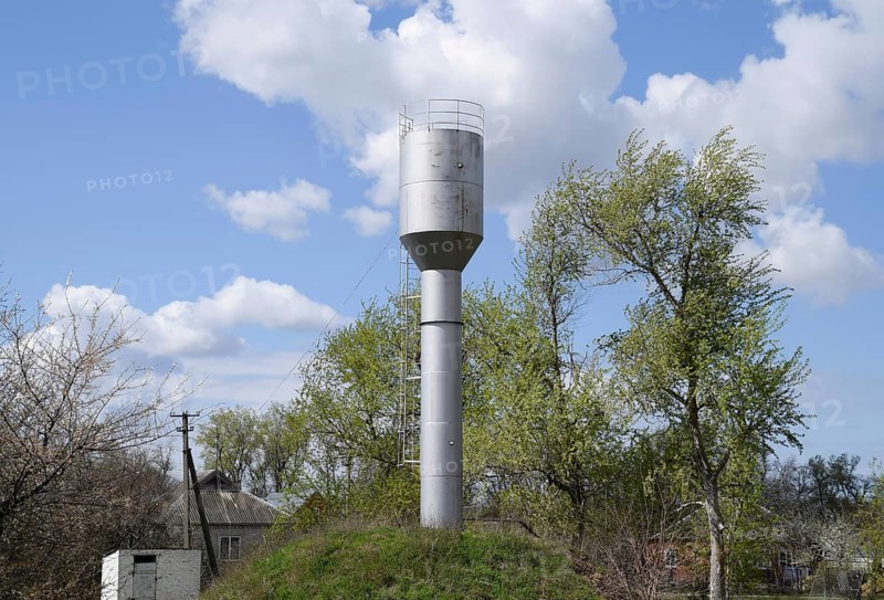 Silver Water Tower among green grass and trees. Atyrau, Kazakhstan