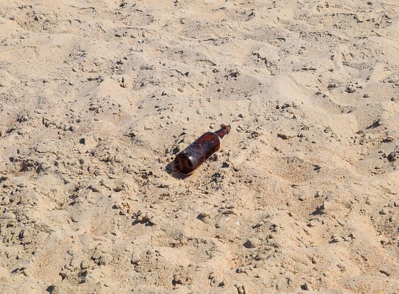 An empty bottle of beer is lying on the sand. Golubitskaya, Russia