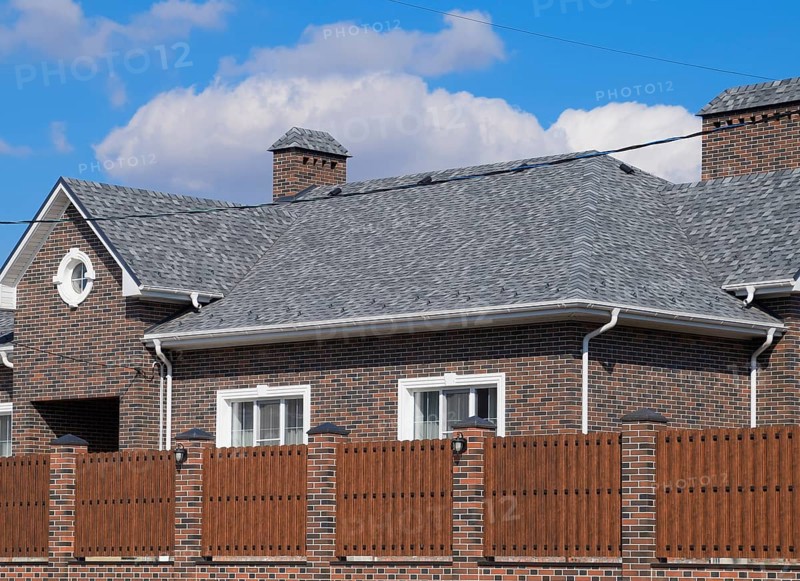 Asphalt shingle. Decorative bitumen shingles on the roof of a brick house. Atyrau, Kazakhstan