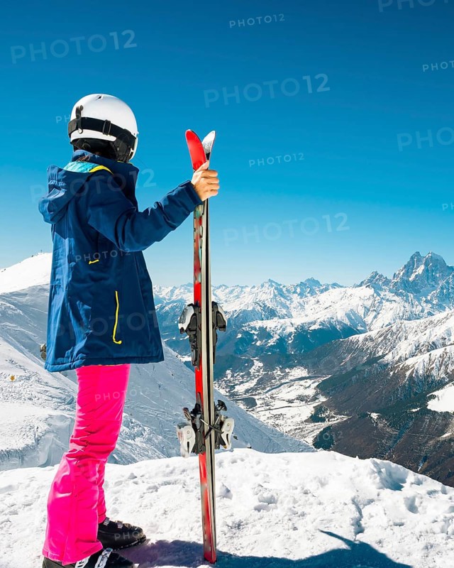 Young caucasian woman pose looking at snowy mountains range in winter. Get away skiing holidays lifestyle. Tetnuldi ski resort viewpoint. Caucasus mountains pristine high altitude freeriding