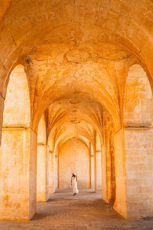 Kasimiye Medrese stone arches with traveler in white dress, iconic historic landmark in Mardin, Southeast Turkey