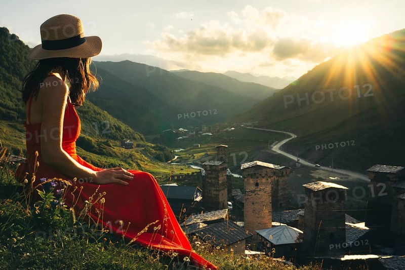 Tourist woman in red dress enjoy view of Ushguli village in Georgia