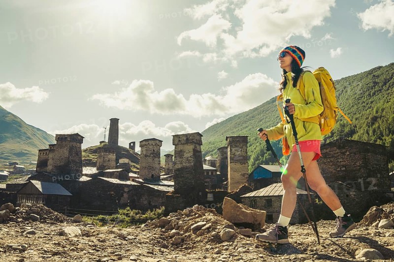 Traveler hiking with backpack and poles in Ushguli, Svaneti mountains, wellness trekking and adventure lifestyle in Caucasus
