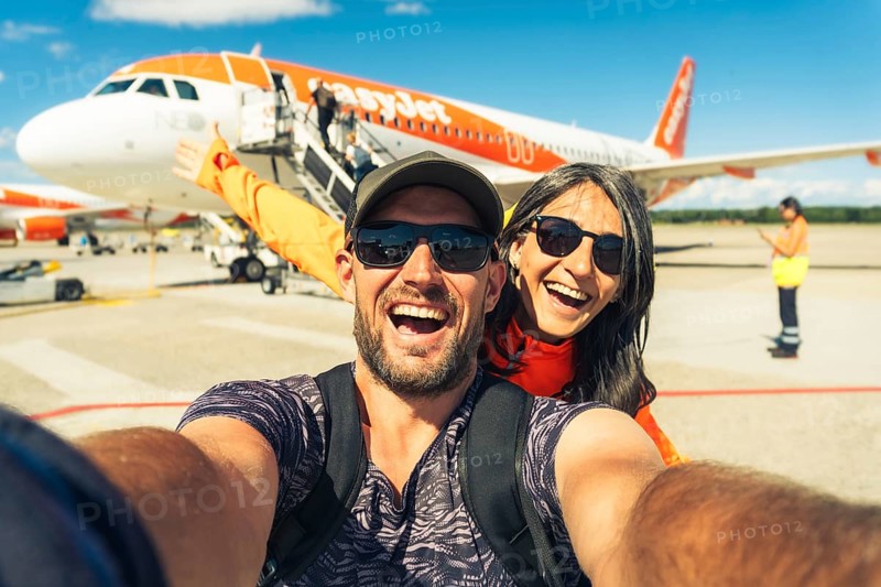 Milan, Italy - 12th august, 2025: happy smiling couple taking selfie in front of EasyJet airplane while boarding at Milan airport during summer travel adventure