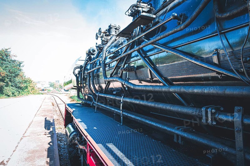Partial view of a shiny steam locomotive showing the detailed mechanics and the railway landscape, Gera, Thuringia, Germany