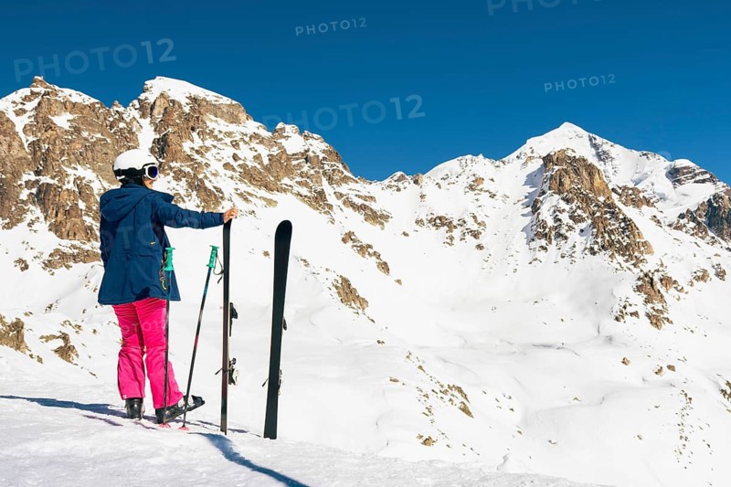 Young caucasian woman pose looking at snowy mountains range in winter. Get away skiing holidays lifestyle. Tetnuldi ski resort viewpoint. Caucasus mountains pristine high altitude freeriding