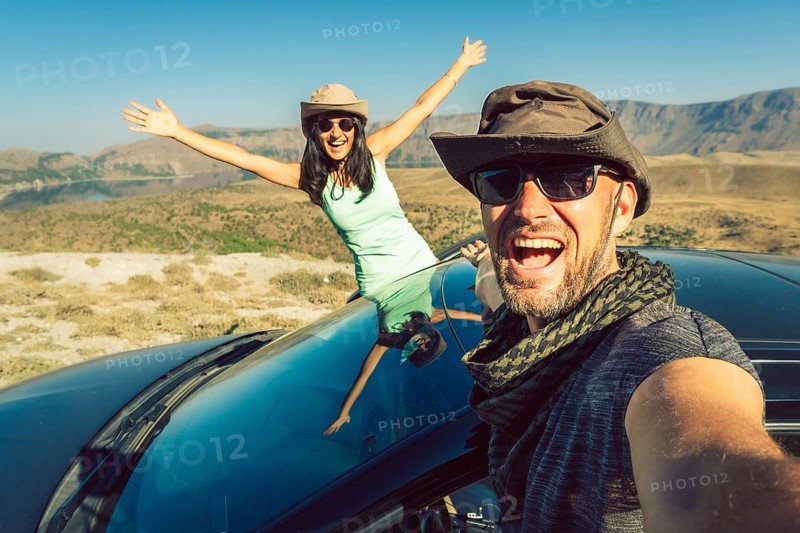 Happy travelers taking selfie photo on summer road trip with rented car in Turkey, symbolizing freedom, travel insurance, car hire lifestyle, and holiday adventure. Nemrut crater travel destination