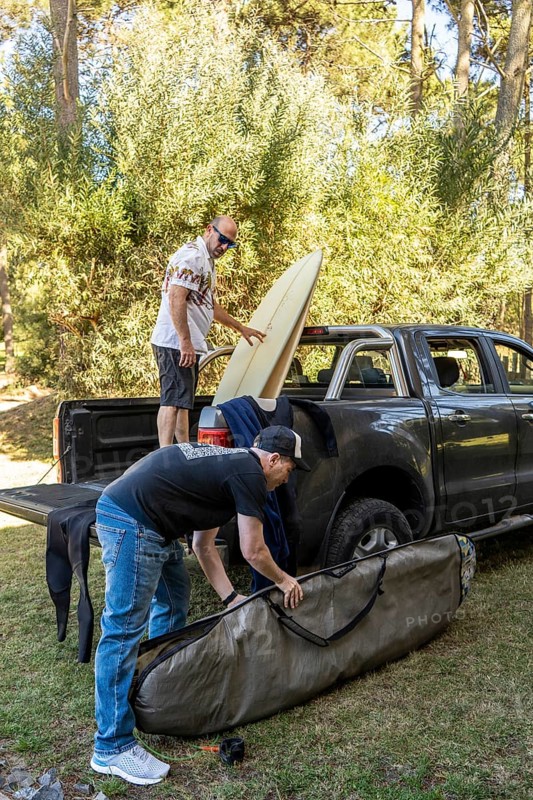 Two men packing surfboards into a truck