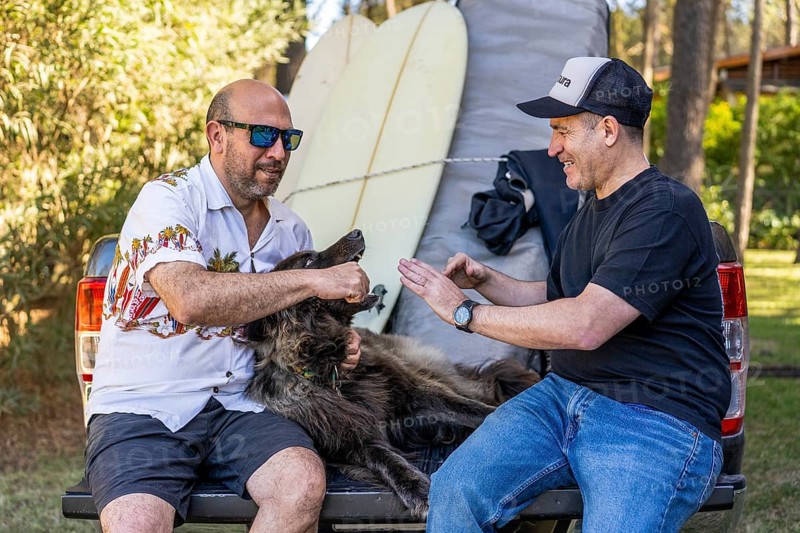 Two men and their dog relaxing on a pickup truck