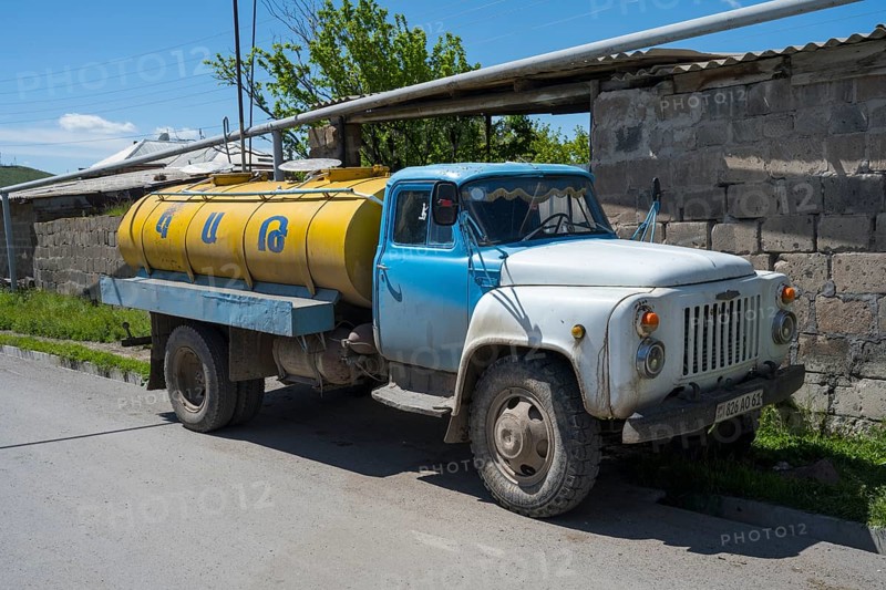 A blue and yellow petrol tanker stands by the roadside in a village, Armenia
