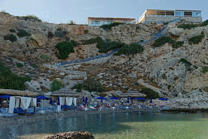 Secluded Grande Blue Beach with blue parasols and clear sea water, Grande Blue Beach, Stegna, Archangelos, Rhodes Island, Greece
