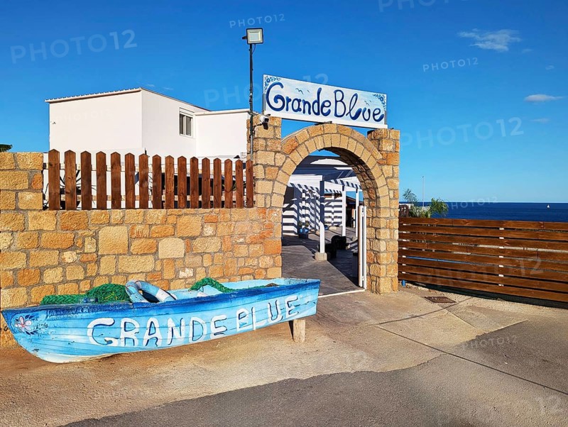 Exterior view of the Grande Blue Restaurant on the coast with a decorative boat and a stone entrance gate, Grande Blue Beach, Stegna, Archangelos, Rhodes Island, Greece