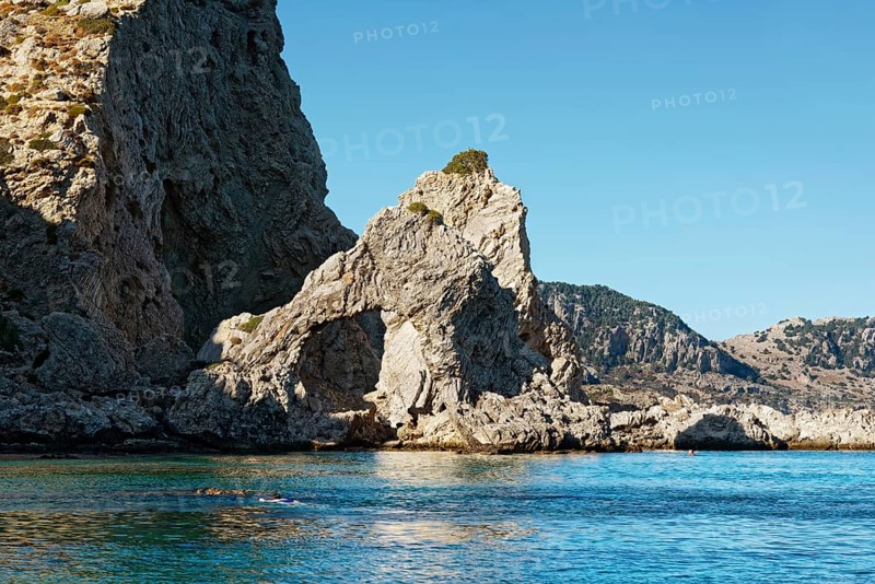 Stone arch at Grande blue beach with clear blue water and sunny sky, showing a natural and peaceful landscape, Grande Blue Beach, Stegna, Archangelos, Rhodes Island, Greece