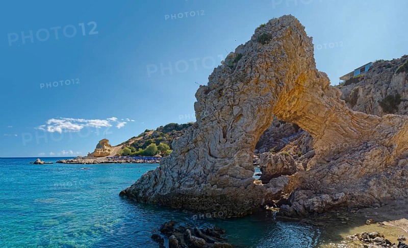 Grande Blue coast with a natural stone arch in front of clear blue water under a sunny sky, Grande Blue Beach, Stegna, Archangelos, Rhodes Island, Greece
