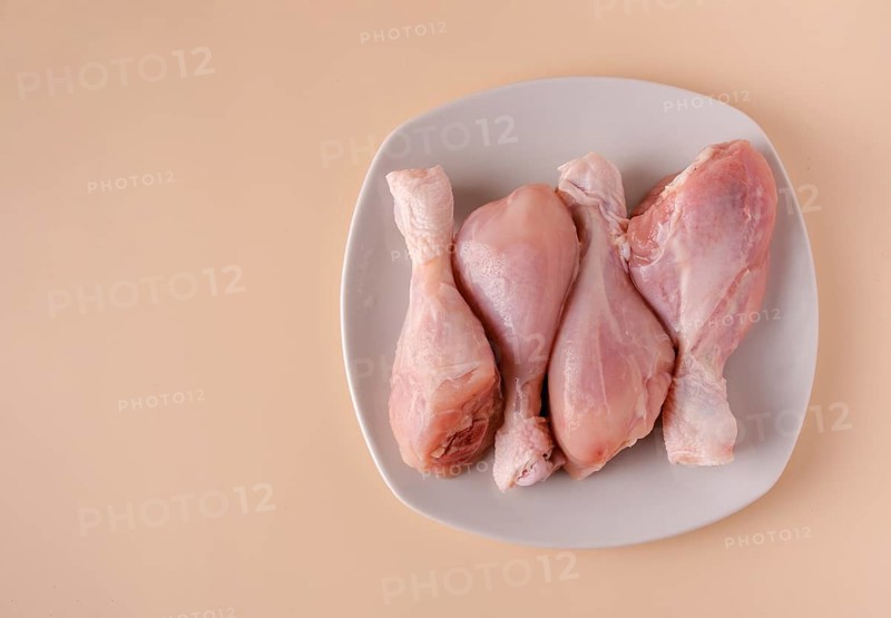 Chicken legs on a plate ready for cooking broth, copy space