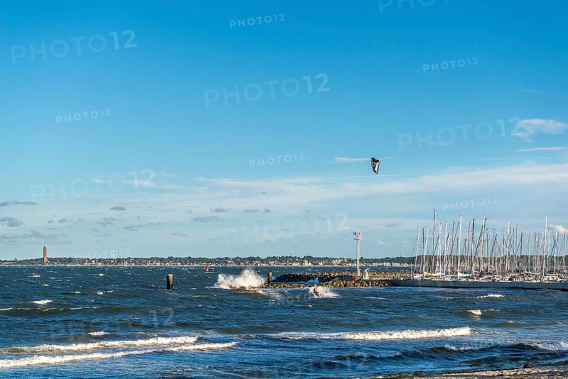 Kitesurfing in the Bay of Kiel in strong winds, high swell, Strande near Kiel, Rendsburg-Eckernförde district, Kiel-Schilksee Olympic and yacht harbour, Baltic Sea Bad Laboe with tower of the naval memorial, sailing, leisure activities, water sports, spray, summer, blue sky, sunshine, Bay of Kiel, Schleswig-Holstein, Germany