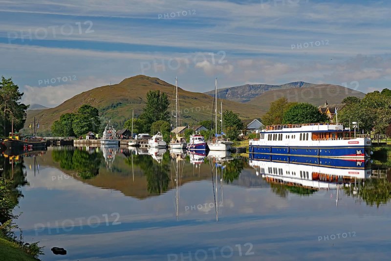 Water reflections of boats in the harbour in front of picturesque mountains, Caledonian Canal, Banavie, Fort William, Scotland, Great Britain